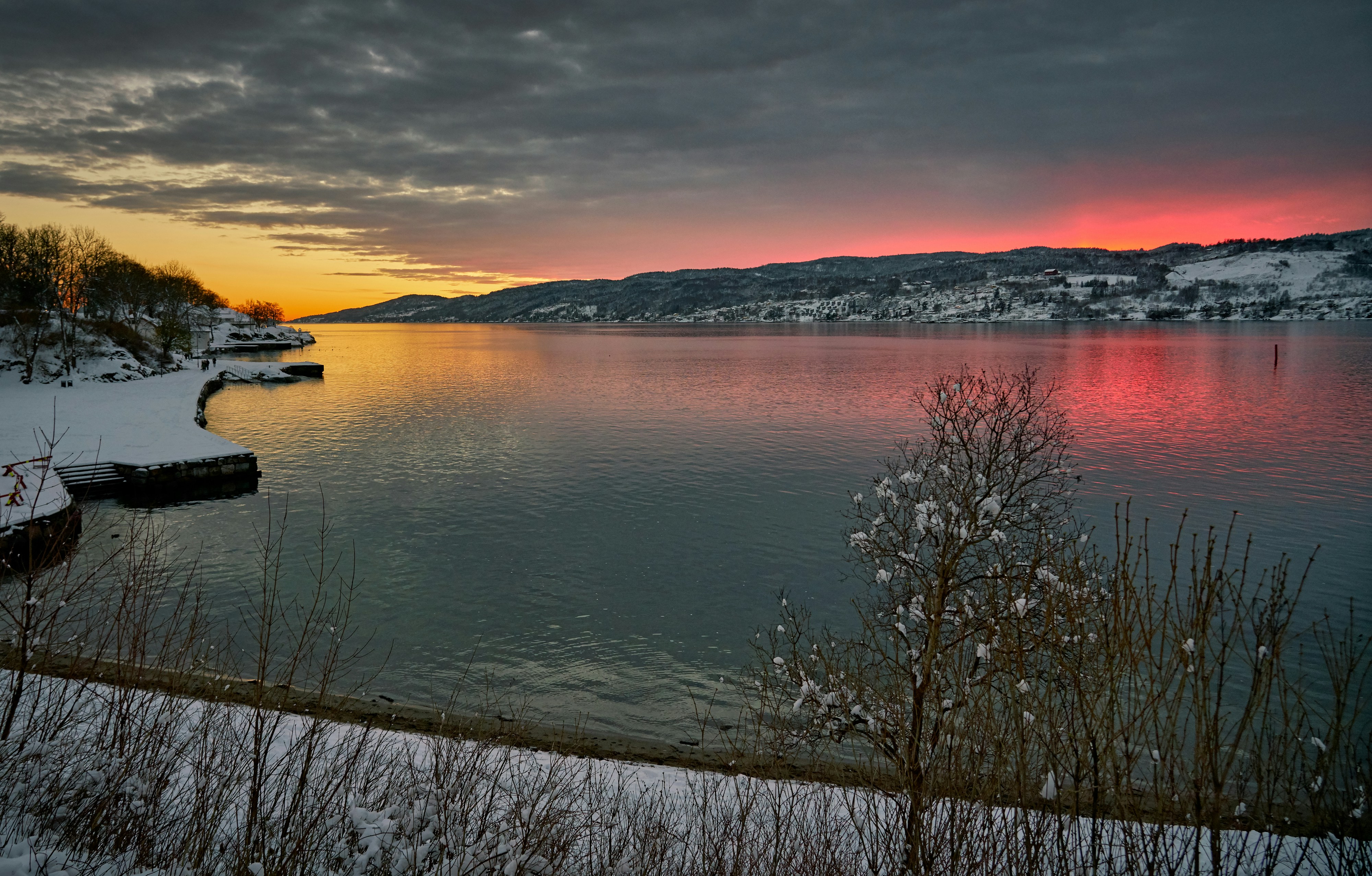 pink and orange sky over partly frozen lake at sunset
