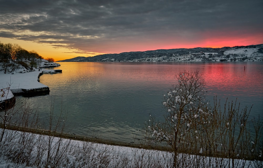 pink and orange sky over partly frozen lake at sunset