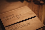 Brown paper bags with the words 'MERRY CHRISTMAS' stamped on them, positioned on a wooden surface.