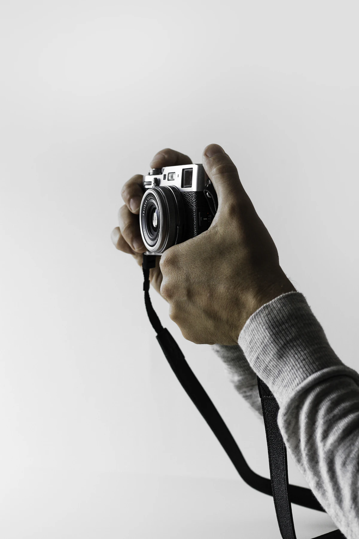 Mão segurando uma câmera fotográfica em fundo branco