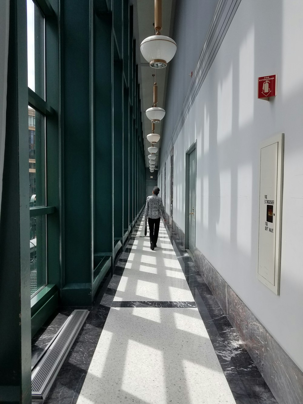 person walking on hallway with pendant lamps