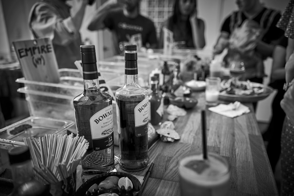 greyscale photography of people sitting on the chair with bottle