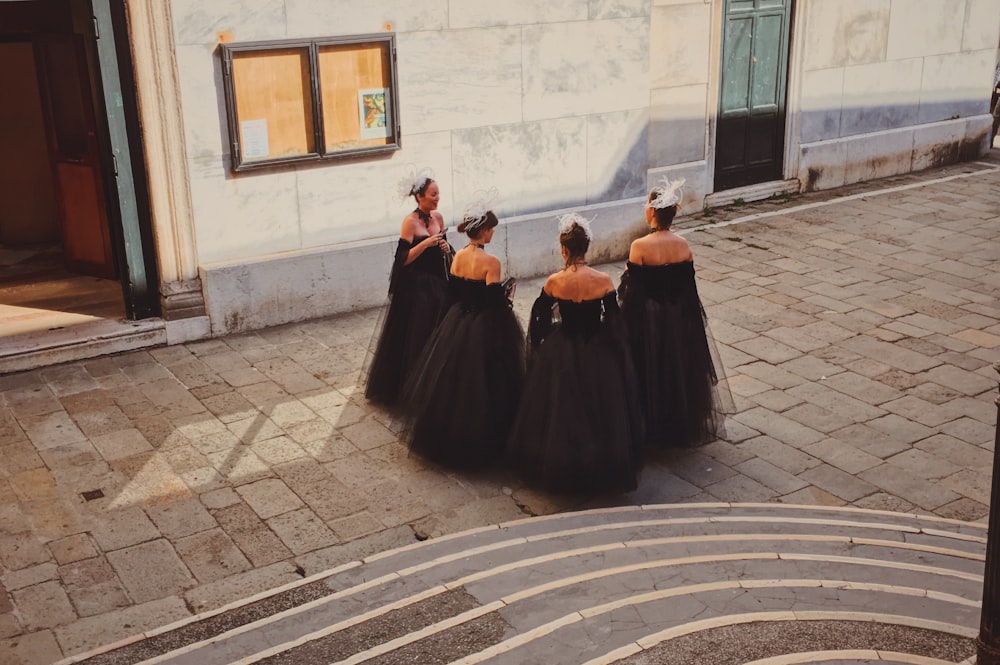 four women standing beside building