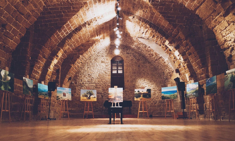 assorted paintings on easel stands inside lighted room