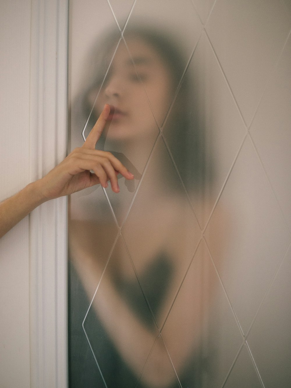 mujer haciendo signo de silencio detrás del espejo