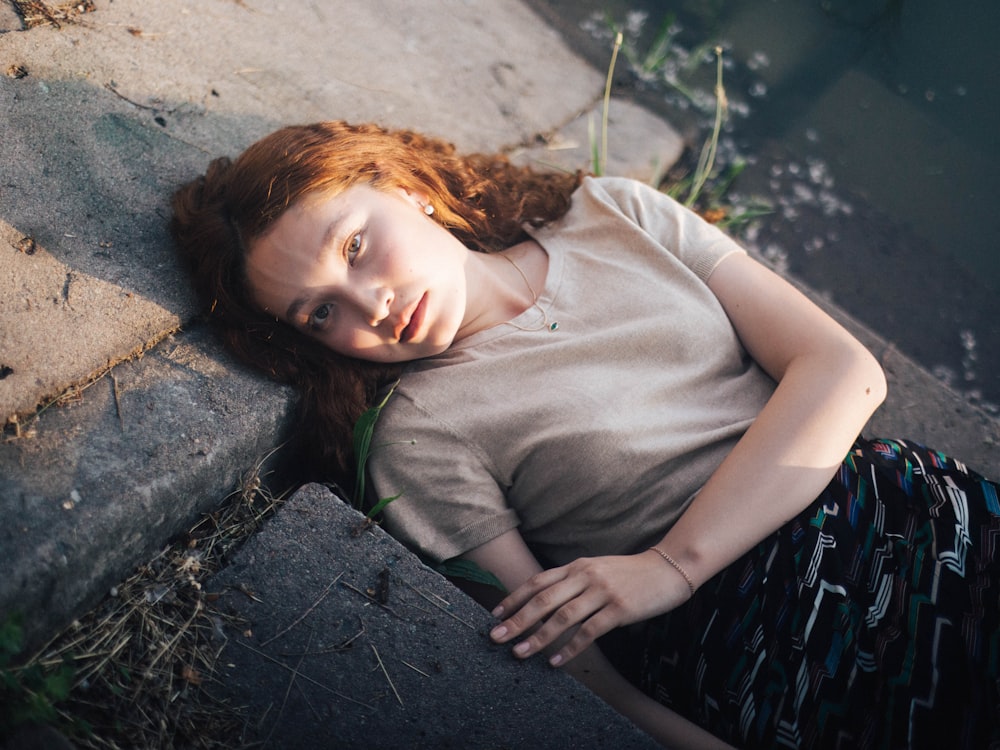 woman lying on grey concrete surface during daytime