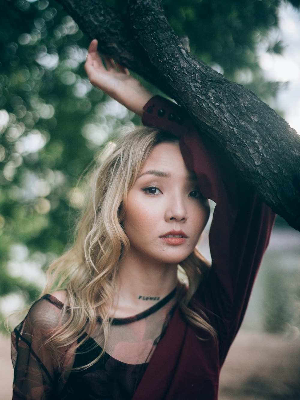 woman leaning her arm on tree branch