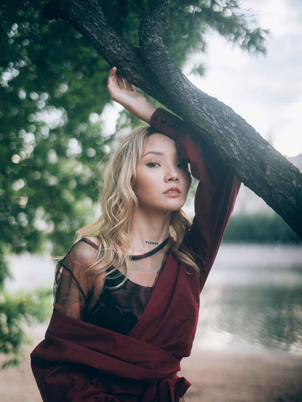 girl wearing red long-sleeved top standing near the body of water during daytime