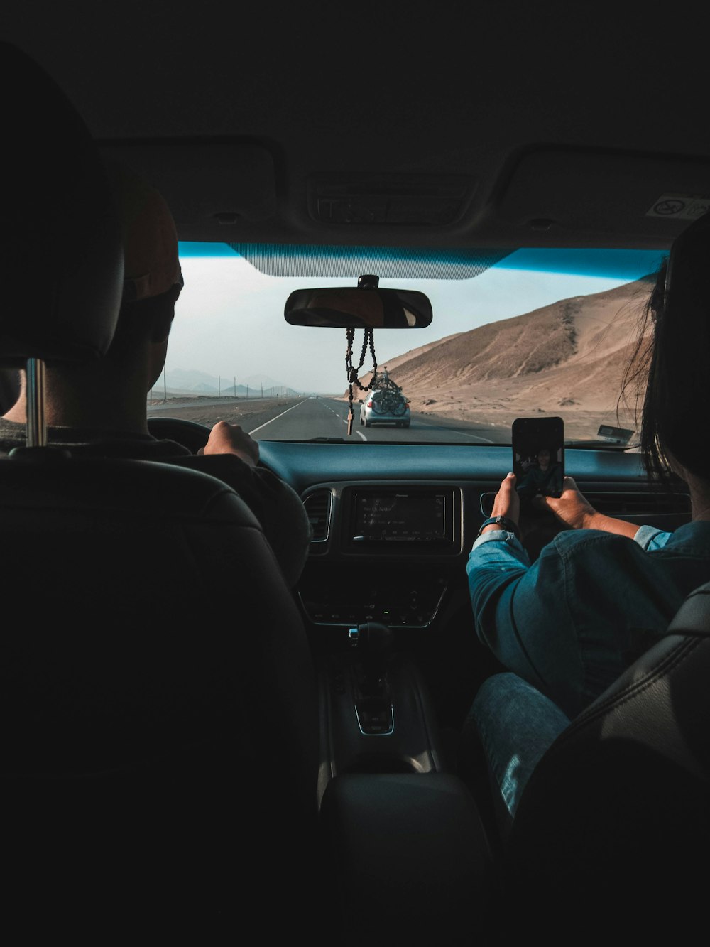 Person, die ein Fahrzeug fährt und ein Smartphone in der Hand hält