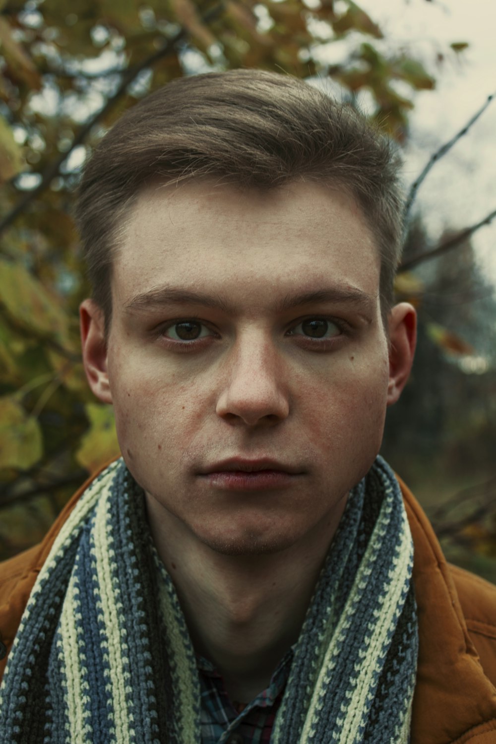 man wearing brown coat with scarf around neck