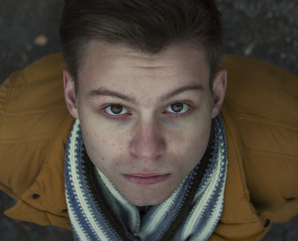 Selektive Fokusfotografie von gelber Jacke und weiß-blau gestreiftem Schal