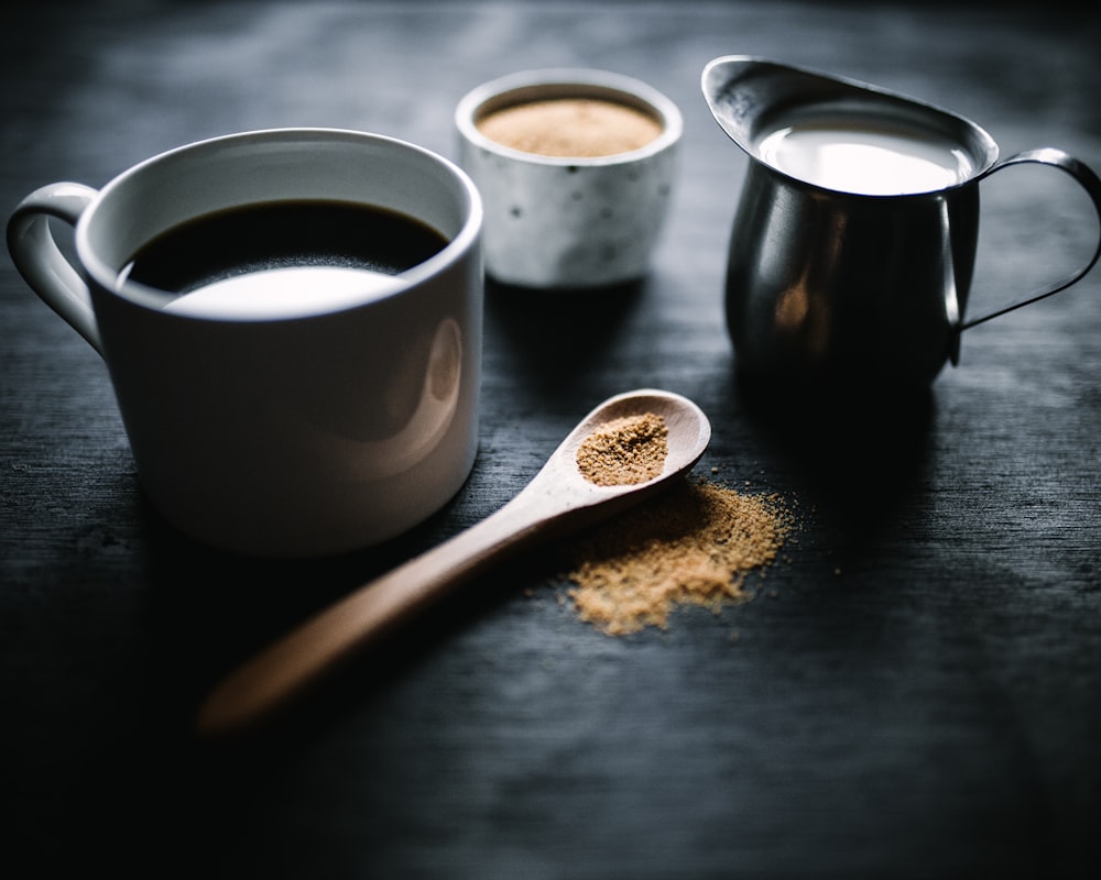 white ceramic mug beside brown wooden spoon