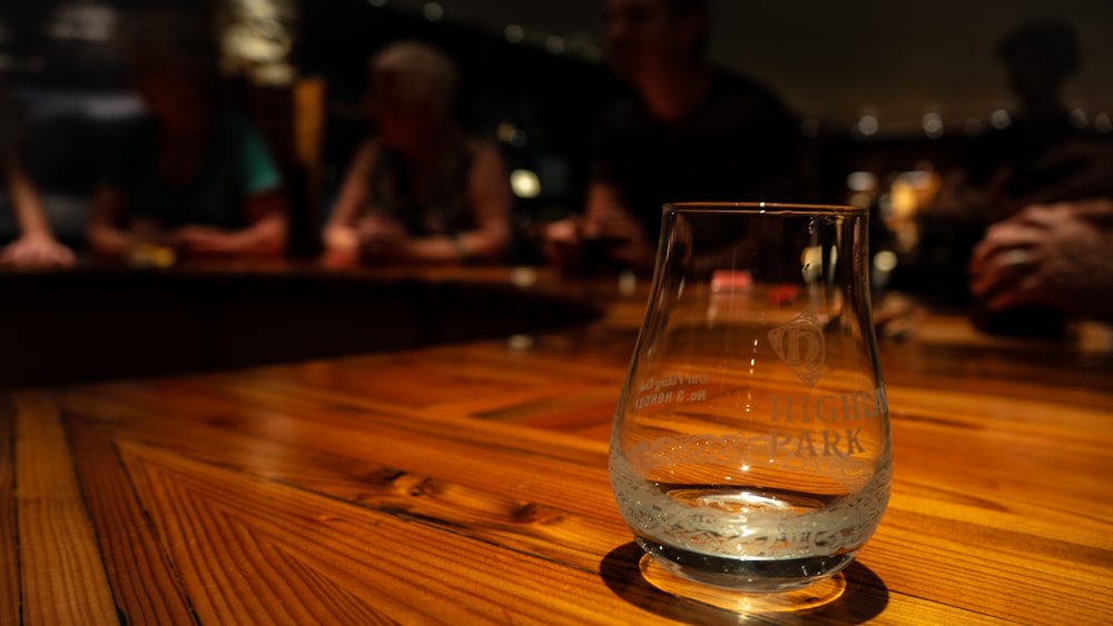 shallow focus photography of clear drinking glass on brown wooden table