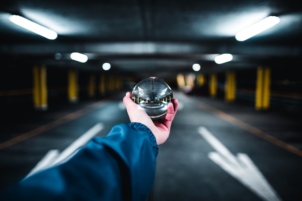 person holding grey glass ball