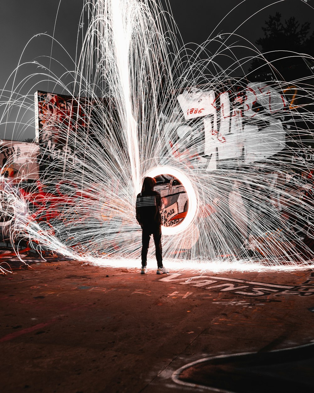 steel wool photography of man near graffiti wall at night