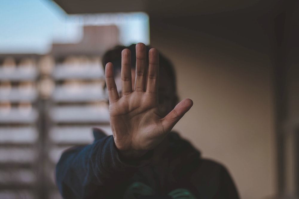 Person standing, holding up their hand to indicate stop.