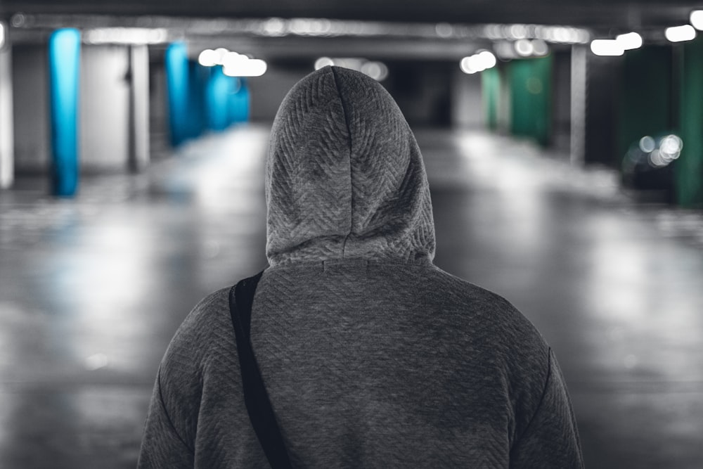 person wearing gray hoodie in parking garage