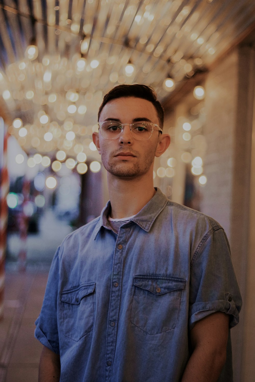 man in blue denim shirt stands in lighted room