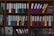 A wooden shelf is filled with various colorful ring binders and folders neatly organized. The binders have labels with text on them and are stacked both horizontally and vertically. Some loose papers and additional documents are tucked among the folders. The scene suggests an office or study environment with a focus on organization.