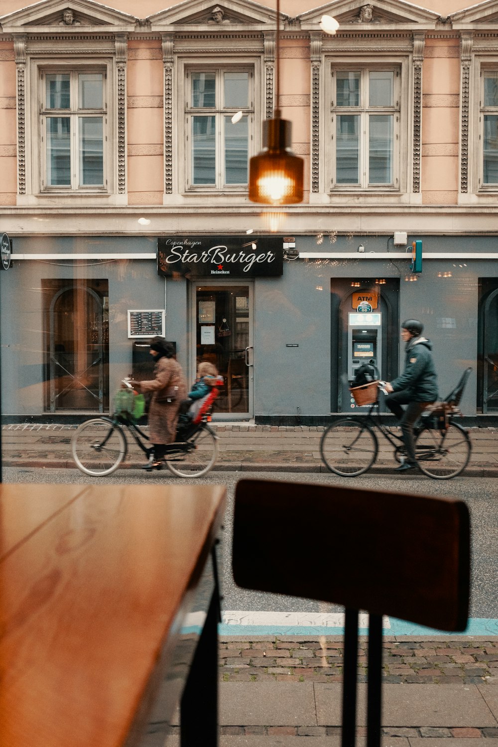 two persons riding bicycle near beige establishment