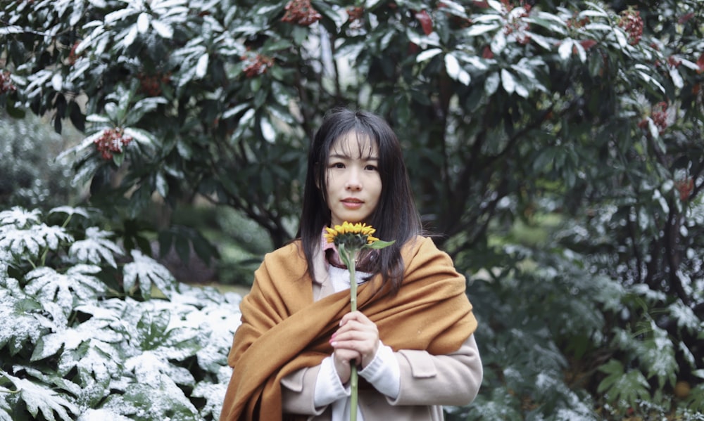 woman in orange shawl holding sunflower