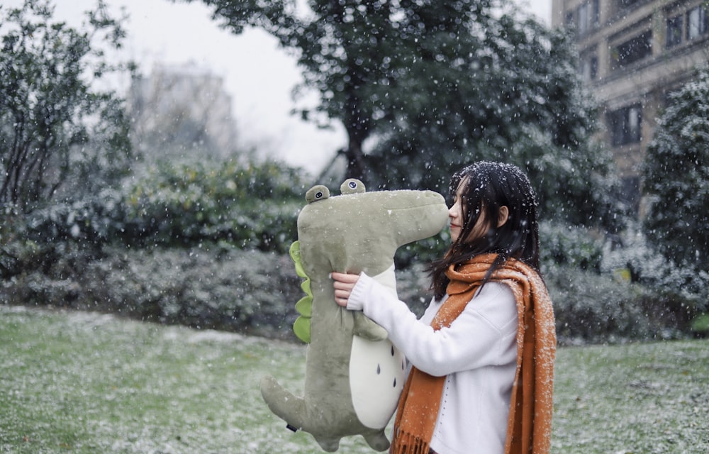 woman carrying dinosaur plush toy outside