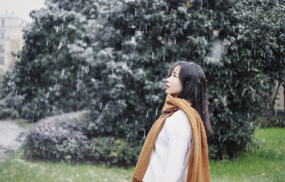 woman in white shirt stands under rain