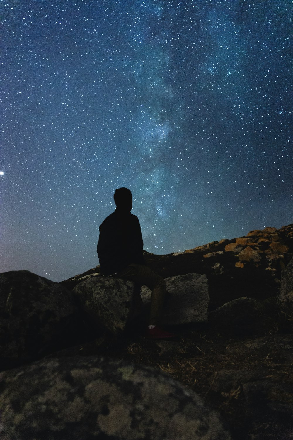 silhouette photography of man sitting on rock