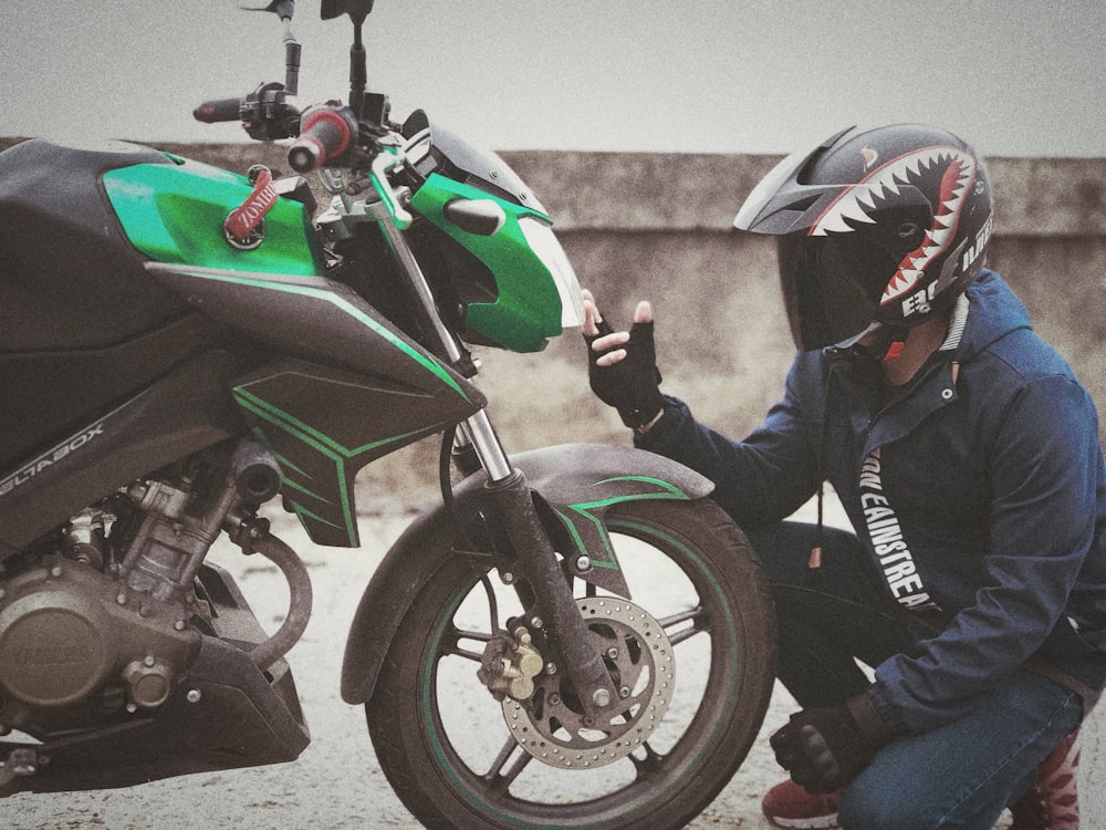 man sitting in front of green motorcycle