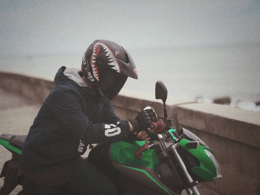 man beside green-and-black motorcycle