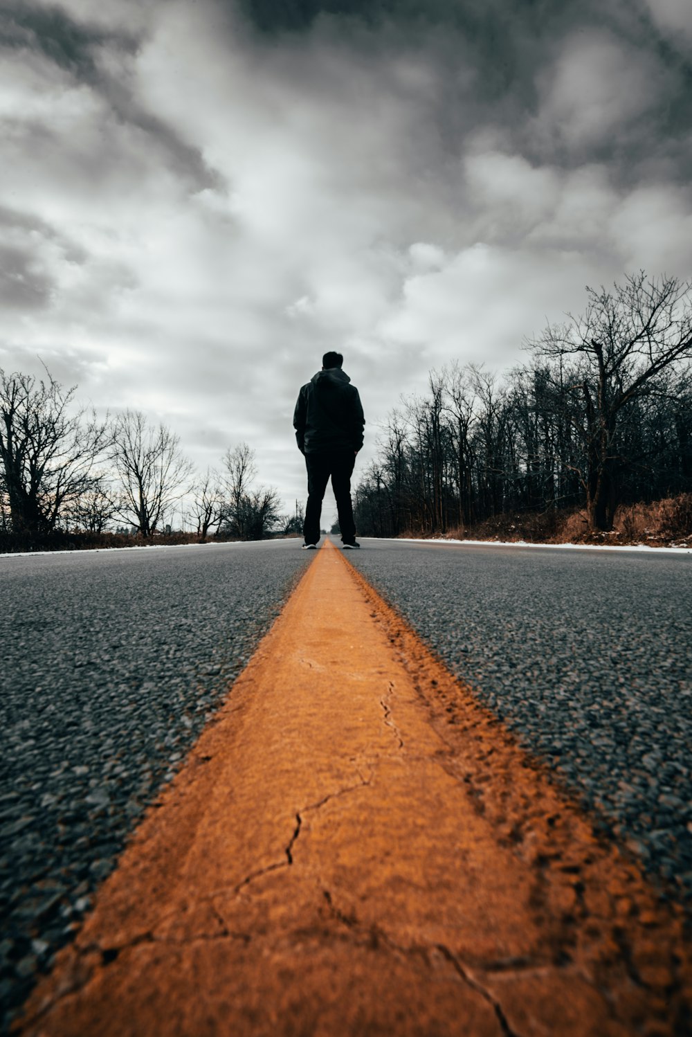 man standing at road under white cloudy sky