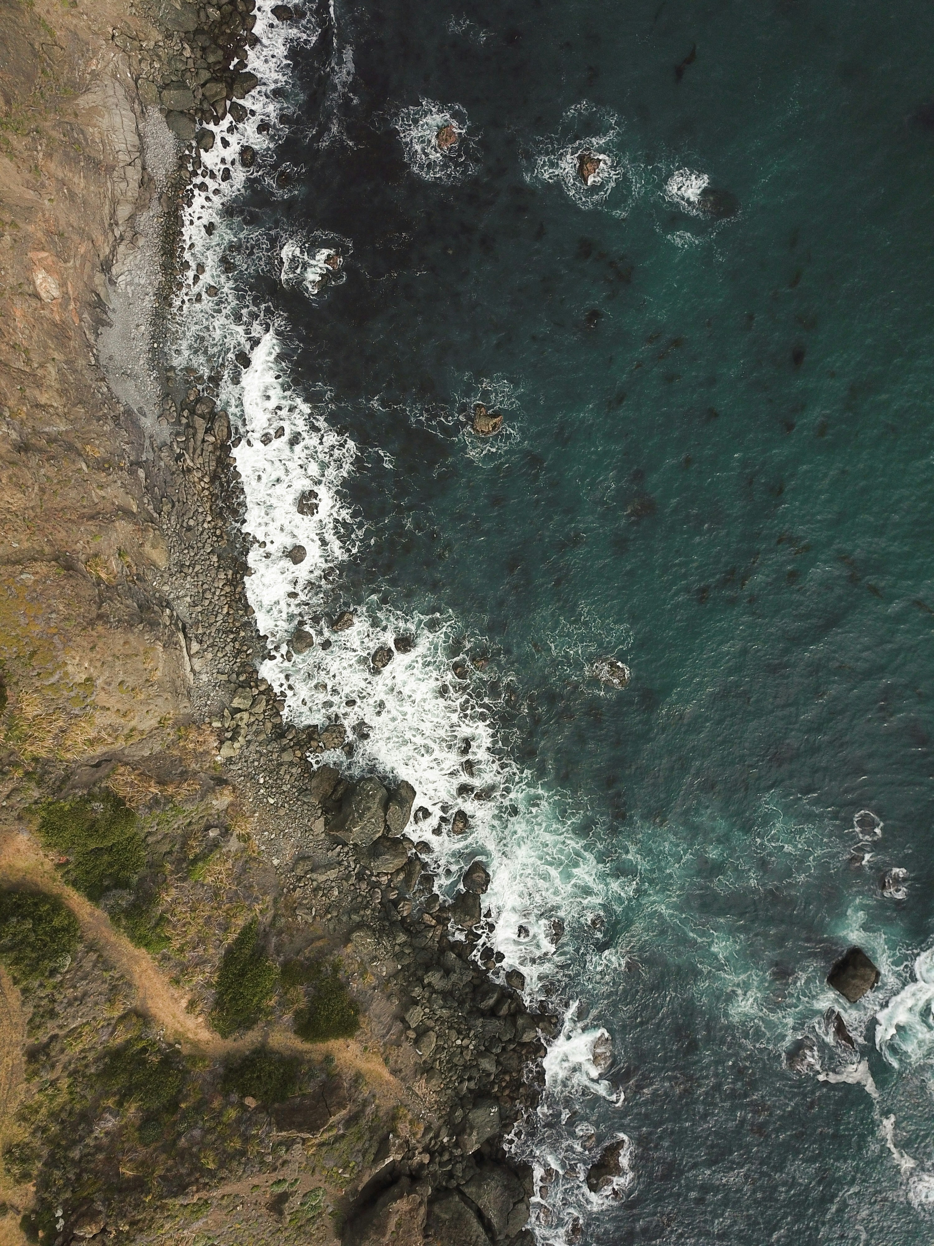 water smashing on rocks near cliff during daytime