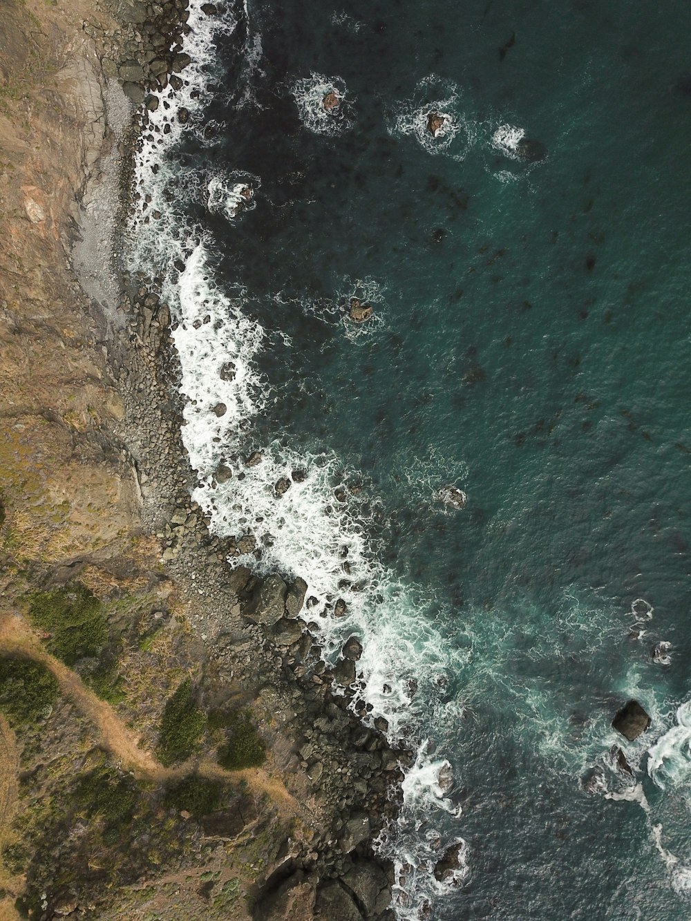 acqua che si infrange sulle rocce vicino alla scogliera durante il giorno