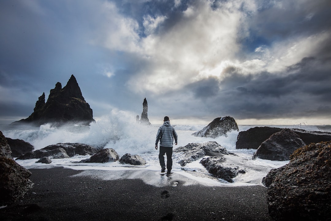 man standing beside beach under white cloudy sky