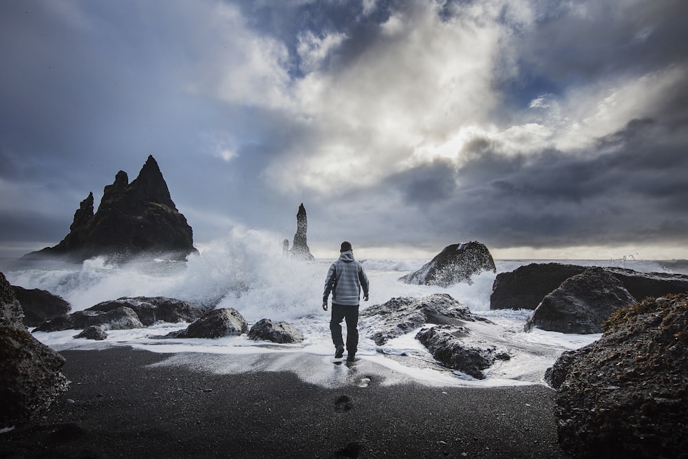 hombre de pie junto a la playa bajo el cielo nublado blanco