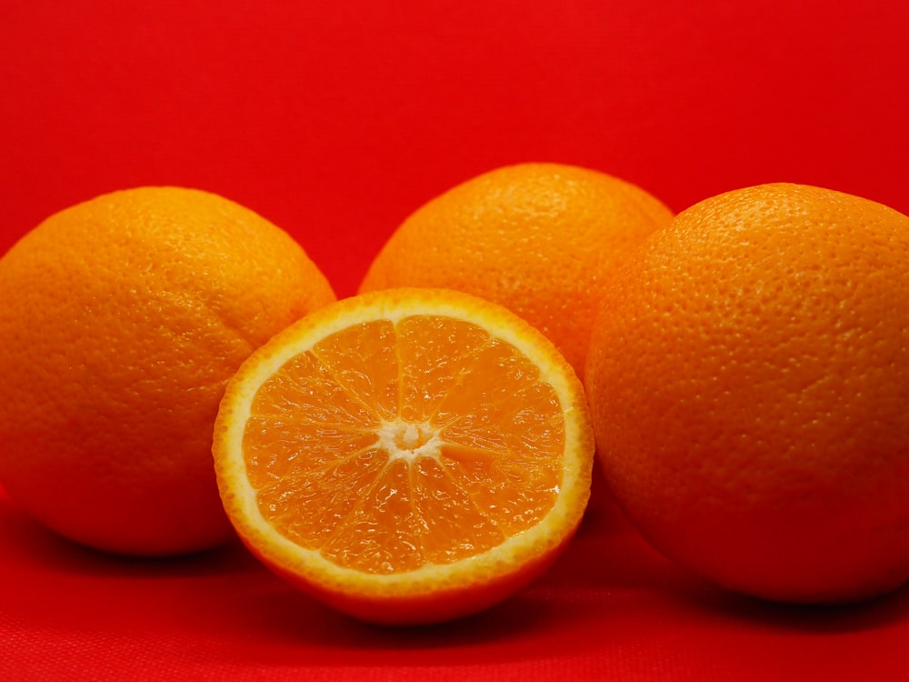 in Scheiben geschnittene Orangenfrüchte neben drei ganzen Orangenfrüchten