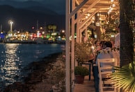 Guests enjoying a sunset dinner on a beachside terrace with fairy lights and elegant table settings.