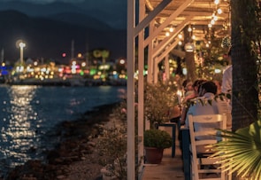 Guests enjoying a traditional dinner on the deck of a wooden dhow under soft lantern light.