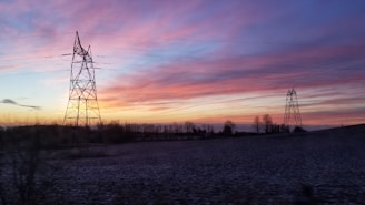 A transmission line stretching across a scenic landscape at sunset.