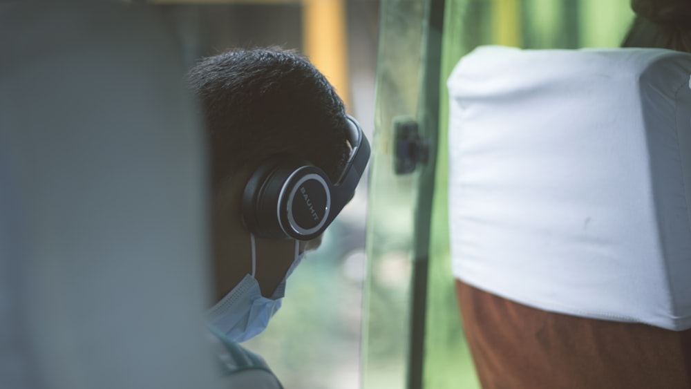 person wearing black wireless headphones and blue mask