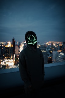 A nighttime cityscape with a person in Lumina Apparel gear standing on a rooftop, the city lights glowing behind them.