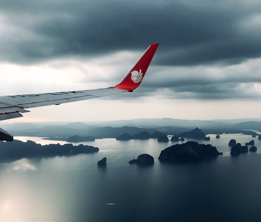 gray and red plane under white cloudy sky