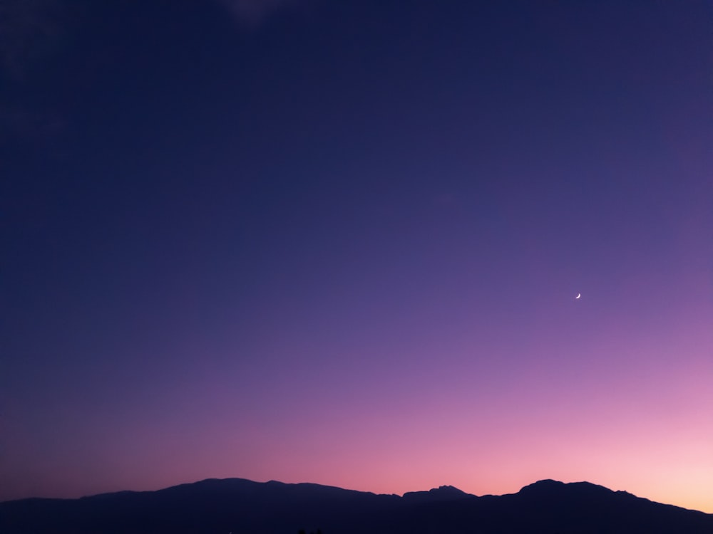 夕暮れ時の丘のシルエットに紫色の空