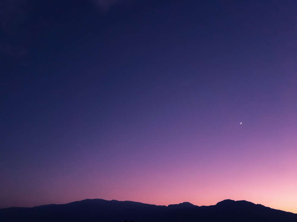 cielo púrpura sobre la silueta de la colina al anochecer