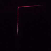 A dark background with a thin, pink neon line forming an L-shape, creating a minimalist and modern aesthetic.
