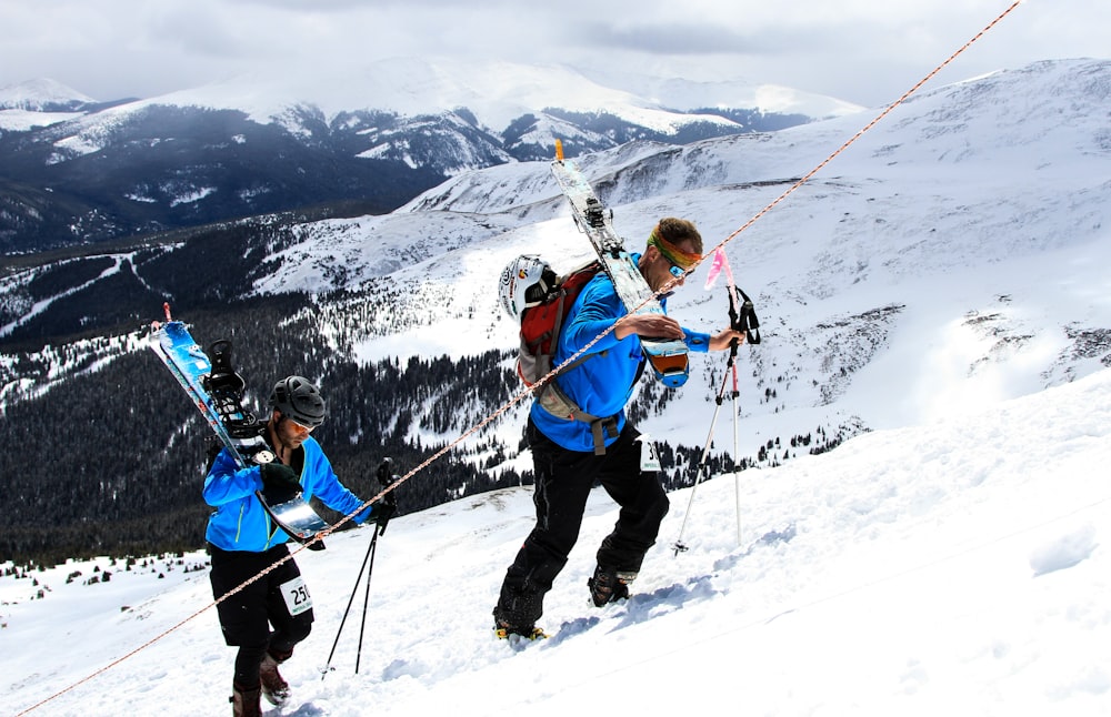 2 men with snowboards going up snow covered slope