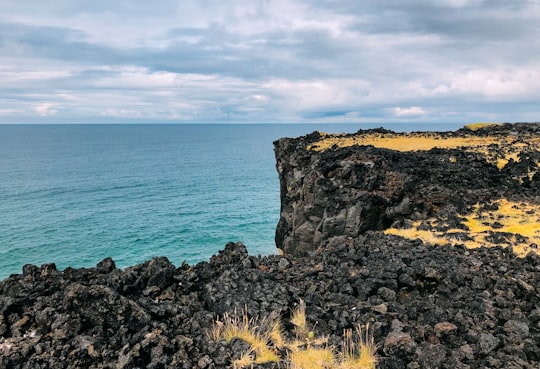 black rocks near body of water in Svörtuloft Lighthouse Iceland