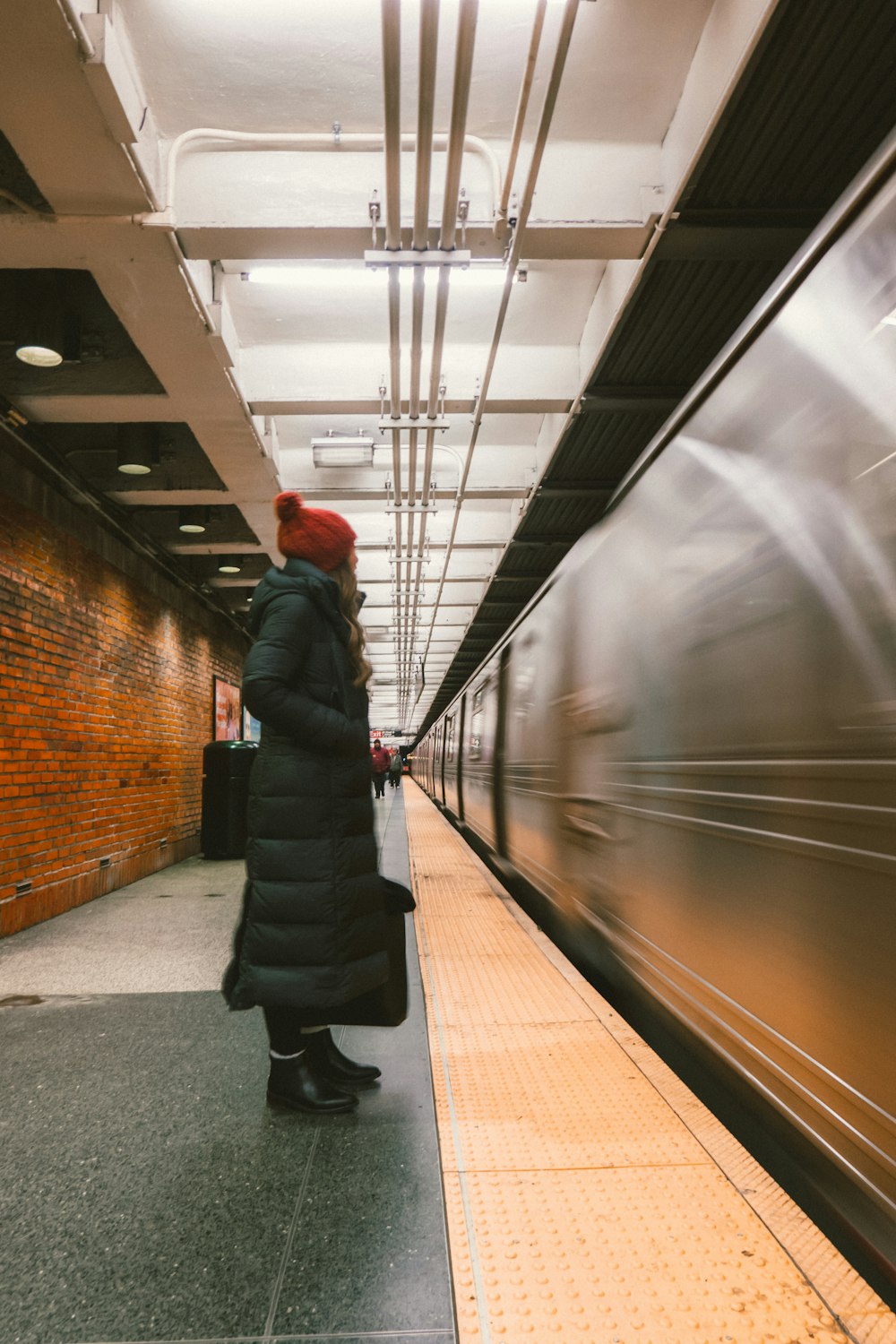 woman wearing bubble trench coat standing in front of train rail