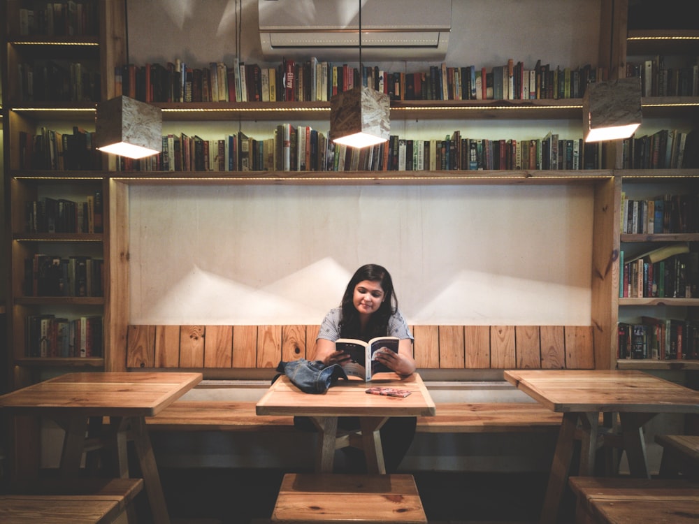 femme lisant un livre à l’intérieur de la bibliothèque