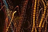 A dynamic display of abstract light patterns featuring swirling, elongated streaks of yellow, blue, and red against a dark background.